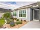 Close-up of the home's entrance and front windows, complemented by attractive landscaping and decorative stone at 6877 Minchew Cir, The Villages, FL 34762