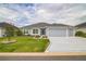 Charming single-story home featuring a well-manicured lawn, colorful landscaping, and a two-car garage at 6877 Minchew Cir, The Villages, FL 34762