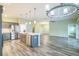 Open-concept kitchen with stainless steel appliances, gray cabinets, island, and hardwood floors at 6877 Minchew Cir, The Villages, FL 34762