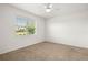Cozy bedroom offers neutral carpeting, a ceiling fan, and a sun-filled window at 7881 Sw 89Th Cir, Ocala, FL 34481