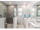 Bright bathroom featuring a large mirror, double sinks, and a walk-in shower with grey tiling at 8802 Sw 79Th Loop, Ocala, FL 34481