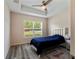 Cozy bedroom boasts tray ceilings, wood-look floors, and a bright window overlooking the front yard at 9432 Se 159Th Ln, Summerfield, FL 34491