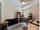 Bedroom featuring a desk, bookcase, dresser, ceiling fan, tray ceiling, and wood-look floors at 9432 Se 159Th Ln, Summerfield, FL 34491