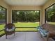 Inviting enclosed patio featuring wicker furniture and screened windows overlooking the serene backyard at 9432 Se 159Th Ln, Summerfield, FL 34491