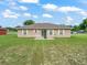 Rear view of a single-story home with a patio, grassy yard, and slider door at 11 Pecan Course Loop, Ocala, FL 34472
