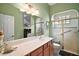 Bathroom features a white sink and vanity, framed mirror and walk-in shower with glass doors at 12169 Se 172Nd Ln, Summerfield, FL 34491