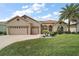 Exterior elevation of home, featuring a well manicured lawn, garden beds, and a large driveway at 12169 Se 172Nd Ln, Summerfield, FL 34491