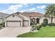 Charming stucco home with a three-car garage, well-manicured lawn, and lovely landscaping at 12169 Se 172Nd Ln, Summerfield, FL 34491