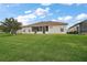 Rear exterior of home has a large grassy lawn with mature landscaping and a screened-in porch at 12169 Se 172Nd Ln, Summerfield, FL 34491
