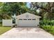 Detached white garage with a decorative accent, large driveway, and vibrant landscaping at 12335 Se 130Th Ct, Ocklawaha, FL 32179