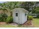 Exterior view of white backyard shed with small window and flowering plants that accentuate the serene landscape at 12335 Se 130Th Ct, Ocklawaha, FL 32179