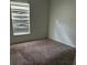 Bedroom featuring neutral carpet, a bright window, and simple white walls at 13155 Sw 73 Ave, Ocala, FL 34473
