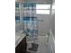 Compact bathroom with a vanity sink, toilet, and bathtub featuring a decorative blue shower curtain at 14126 Greater Pines Blvd, Clermont, FL 34711