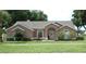 Attractive single-story home with manicured lawn, arched entryway, and mature trees at 14126 Greater Pines Blvd, Clermont, FL 34711