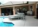Outdoor covered patio featuring a lounge chair, grill, outdoor dining area, and access to the pool at 14126 Greater Pines Blvd, Clermont, FL 34711