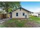 Exterior view of house's backyard showcasing grass, trees, and an access door at 1434 Se Silver Springs Pl, Ocala, FL 34471