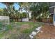 Backyard view with a storage shed and green house adjacent to a green lawn and trees at 1434 Se Silver Springs Pl, Ocala, FL 34471