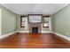 Bright living room showcasing original hardwood floors, a vintage brick fireplace, and large windows at 1434 Se Silver Springs Pl, Ocala, FL 34471