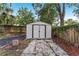 Storage shed in the backyard with a gray metal door and surrounding greenery at 1434 Se Silver Springs Pl, Ocala, FL 34471