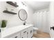 Bathroom featuring a modern vanity, black hardware, a round mirror, and floating shelves at 15621 Se 103Rd Ter, Summerfield, FL 34491