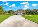 Long driveway leading to a two-story home with a two-car garage, and manicured landscaping at 15621 Se 103Rd Ter, Summerfield, FL 34491