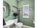 Stylish powder room with green walls, wood shelves, and a round mirror at 1814 Nw 44 Court Rd, Ocala, FL 34482