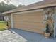 Attached garage featuring stone accents, a brown door, and decorative plants at 21511 Sw Plantation Sw St, Dunnellon, FL 34431