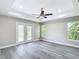 A spacious bedroom with two windows, a ceiling fan, a tray ceiling, and French doors to the backyard at 226 Locust Ln, Ocala, FL 34472