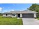 Charming single-story home with a well-manicured lawn and a gray two-car garage door at 226 Locust Ln, Ocala, FL 34472