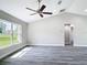Spacious living room with gray floors, vaulted ceiling, ceiling fan, and view of the front yard at 226 Locust Ln, Ocala, FL 34472