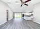 Spacious living room with gray floors, vaulted ceiling, ceiling fan, and access to kitchen and sliding glass door at 226 Locust Ln, Ocala, FL 34472