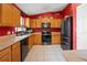 Well-lit kitchen with oak cabinets, modern black appliances, and complemented by the bold red walls at 32 Dogwood Drive Loop, Ocala, FL 34472
