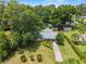 An aerial view of a single-story home that features a long driveway and lush landscaping, including large trees and manicured bushes at 3621 Se 12Th Pl, Ocala, FL 34471
