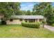 A single-story home featuring a metal roof, a long, covered carport, and manicured landscaping at 3621 Se 12Th Pl, Ocala, FL 34471