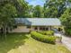 A single-story home featuring a metal roof, a long, covered carport, and manicured landscaping at 3621 Se 12Th Pl, Ocala, FL 34471