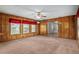 Spacious living room with paneled walls, a ceiling fan, windows, and neutral carpeting at 3621 Se 12Th Pl, Ocala, FL 34471