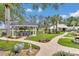 Lush backyard featuring manicured lawn, a covered bar area, and pathway to white farmhouse at 4550 County Road 104, Oxford, FL 34484