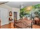 Bedroom features a statement wall mural of a forest, black metal bed frame and wood floors at 4550 County Road 104, Oxford, FL 34484