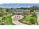 Stunning brick home featuring manicured lawn, circular drive with fountain, and lush tropical landscaping at 4550 County Road 104, Oxford, FL 34484