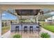 Outdoor bar area with seating, lighting, and a view of the backyard and white farmhouse at 4550 County Road 104, Oxford, FL 34484