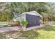 Charming shed featuring black doors, white trim, and surrounding lush greenery adding to the property's appeal at 4550 County Road 104, Oxford, FL 34484