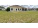 Back exterior features a screened lanai and a spacious yard with mature landscaping at 5551 Nw 25Th Loop, Ocala, FL 34482