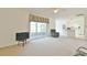Open living room with neutral carpet, ceiling fan, and sliding glass door to the lanai at 5551 Nw 25Th Loop, Ocala, FL 34482