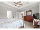 A primary bedroom with a tray ceiling, ceiling fan, wood floors, and a wooden dresser is bright and ready for a new owner at 7891 Sw 89Th Cir, Ocala, FL 34481