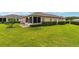 Spacious backyard featuring manicured lawn, mature landscaping, and a cozy screened lanai at 8670 Se 141St Pl, Summerfield, FL 34491