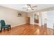 Spacious bedroom featuring wood floors, ceiling fan, adjacent bathroom and a classic wooden dresser at 8670 Se 141St Pl, Summerfield, FL 34491