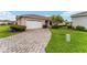 Charming home featuring a brick driveway, attached garage, manicured lawn, and beautiful landscaping at 8670 Se 141St Pl, Summerfield, FL 34491