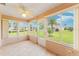 Bright sunroom with tile flooring and panoramic windows offering views of the lush lawn and mature landscaping at 8670 Se 141St Pl, Summerfield, FL 34491
