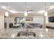 View of kitchen island with granite countertop, stainless steel sink, and open floor plan to living and dining areas at 8878 Sw 103Rd Cir, Ocala, FL 34481