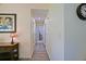 Long hallway with wood floor leading to bedrooms, decorated with artwork and a clock on the wall at 9486 Se 173Rd Pl, Summerfield, FL 34491